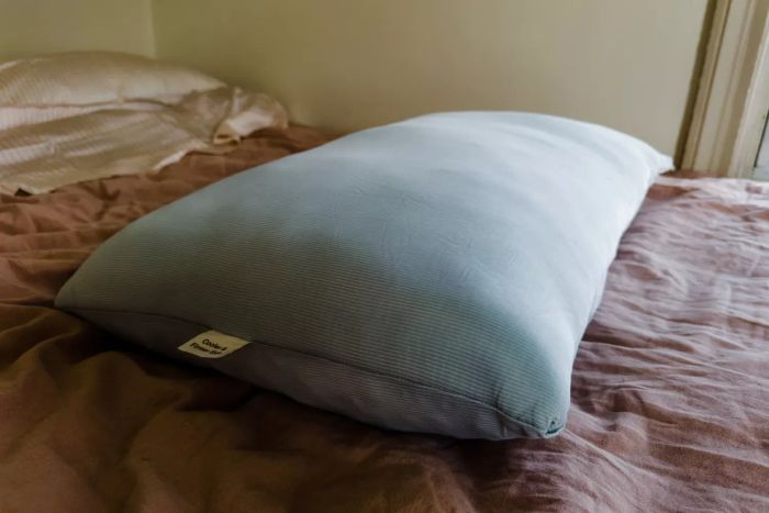 The Coop EdenCool+ Adjustable Pillow placed on a bed