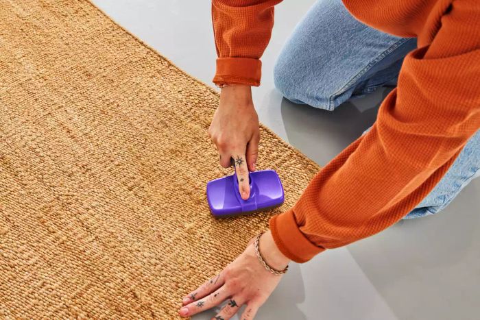 A person brushing the Revival Hart Jute Rug