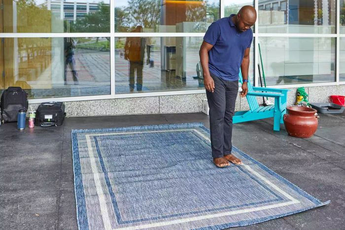 A person walking barefoot on the Unique Loom Outdoor Collection Transitional Indoor/Outdoor Area Rug