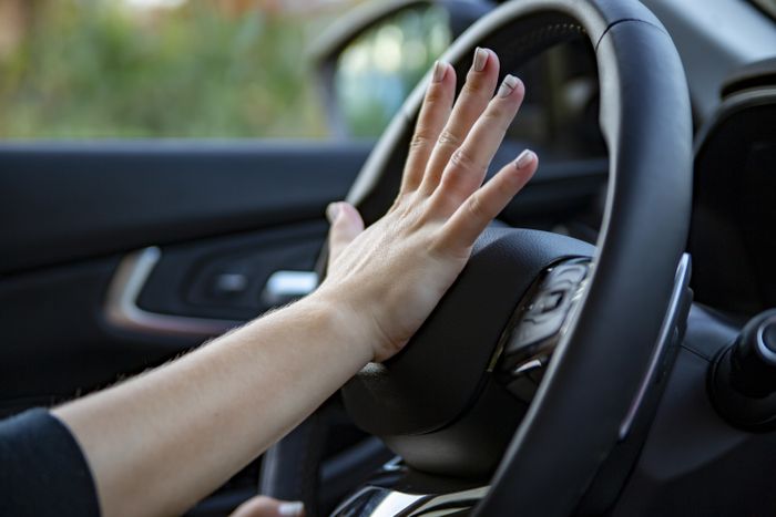 A close-up shot of a hand pressing a car horn