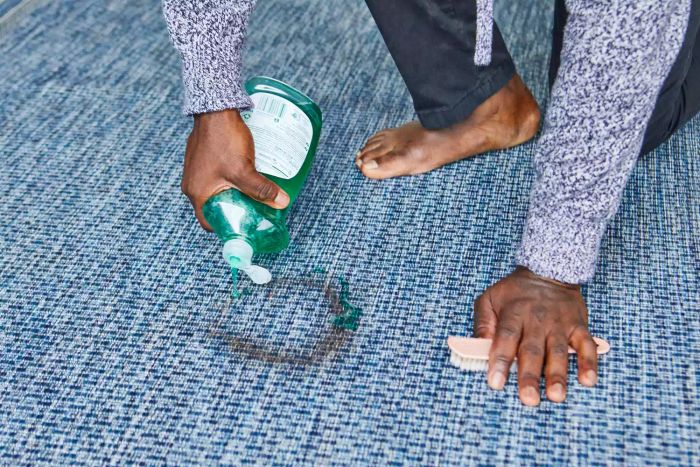 A person pouring liquid soap onto the Unique Loom Outdoor Collection Transitional Indoor/Outdoor Area Rug