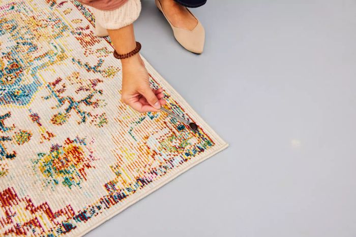 A person spooning a stain onto the Safavieh Crystal Collection Rug