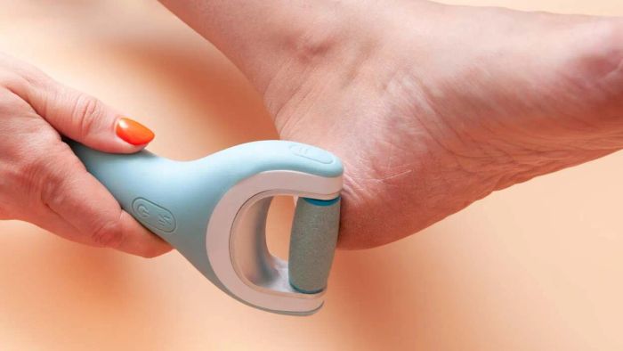A woman applies an electric roller file to her calluses