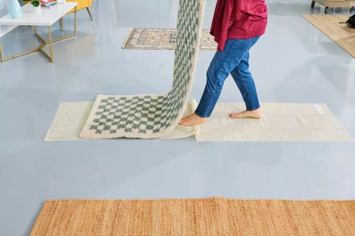 A person placing the AllModern Walker Checkered Shag Area Rug onto a rug pad