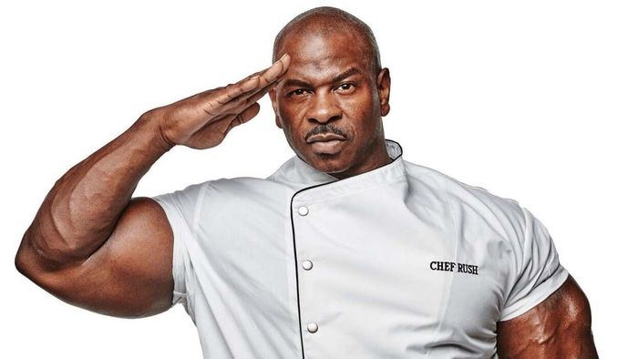 Andre Rush, dressed in his chef’s attire, salutes the camera with confidence