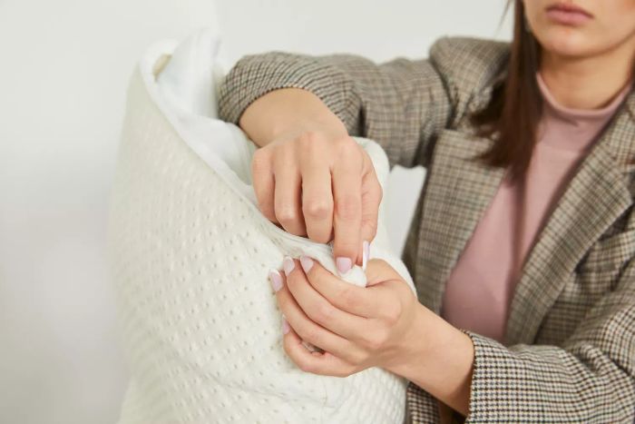 A person holding the corner of a Snuggle-Pedic Adjustable Shredded Memory Foam Pillow