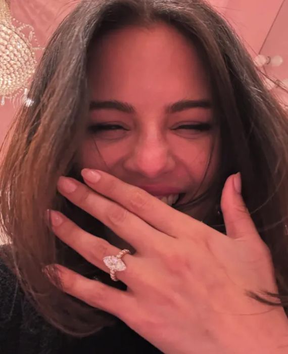 Selena Gomez smiles with her hand covering her mouth, showcasing a glittering engagement ring