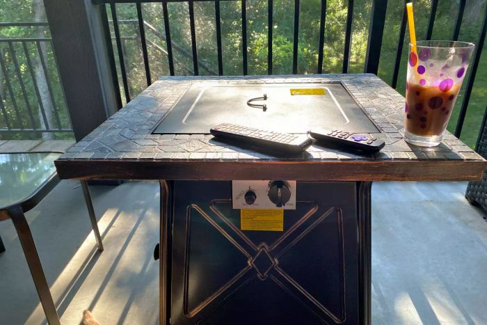 The Hampton Bay Crossridge Gas Fire Pit displayed on an outdoor deck