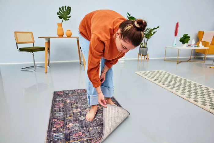 A person inspecting the bottom of the Rifle Paper Co. Provence Joliette Rug