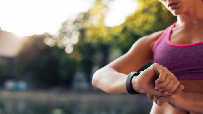 A woman dressed in workout gear checking her watch