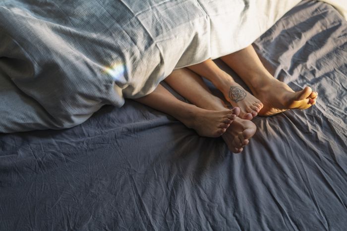 two pairs of feet resting on a bed