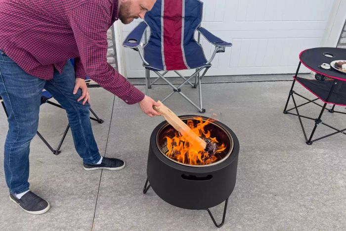 A person lighting wood in the Tiki Social Smokeless Fire Pit
