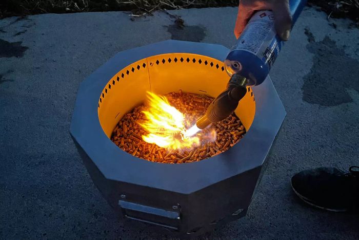 A hand using a torch to ignite the Inno Stage Portable Smokeless Fire Pit