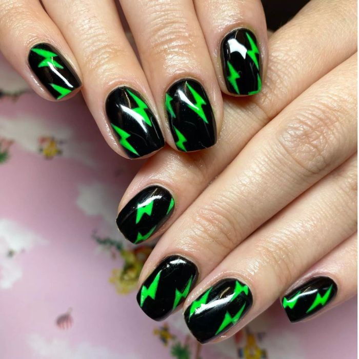 Black manicure with neon green lightning bolts.