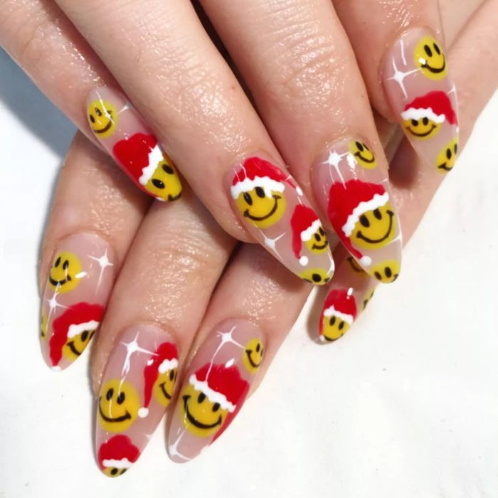 Nude nails featuring cheerful smiley faces adorned with Santa hats.