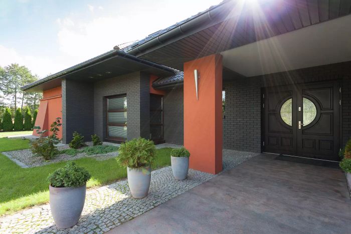 A front door on a black house with copper-toned accents