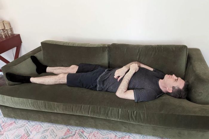 A person relaxes on the Maiden Home The Varick Couch.