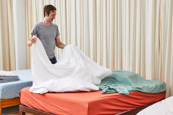 An individual adjusting the Buffy Breeze Comforter on a bed