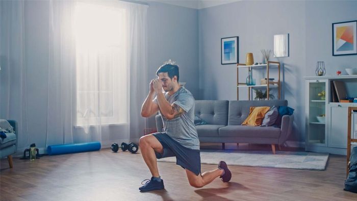 A man performing lunges in his living room