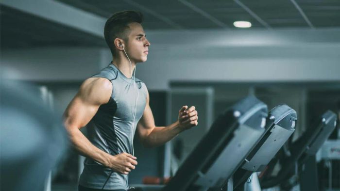 A muscular individual sprinting on a treadmill