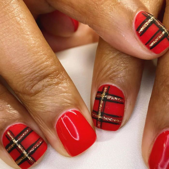 A striking manicure featuring a bold red and red plaid pattern.