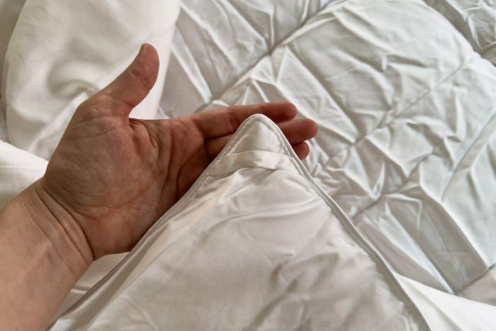 Someone is adjusting the corner of the Sijo Clima Tech TempTune Comforter