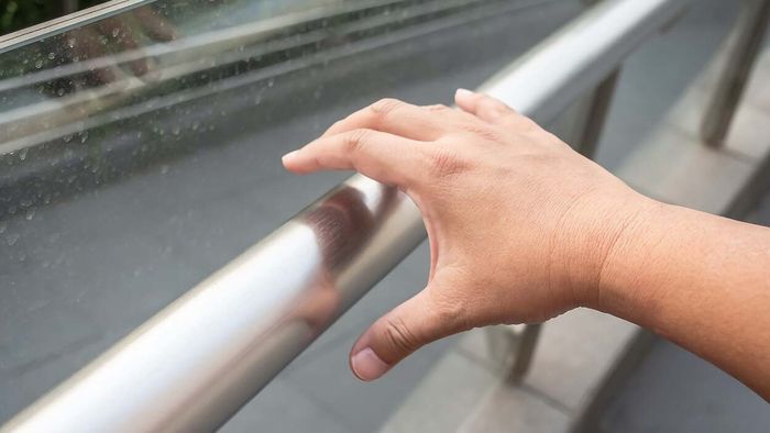 hand reaching out to hold onto a public handrail