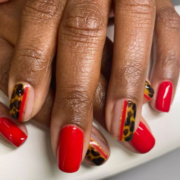 A bold manicure combining vibrant red with trendy cheetah prints.