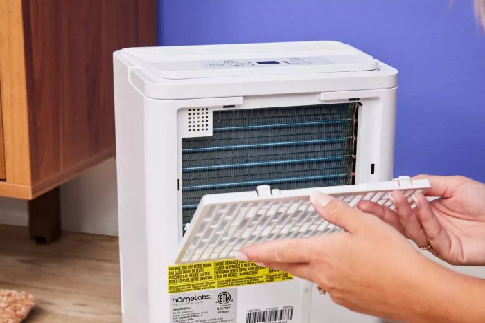 Two hands detaching a grate from the Homelabs 8-Pint Dehumidifier
