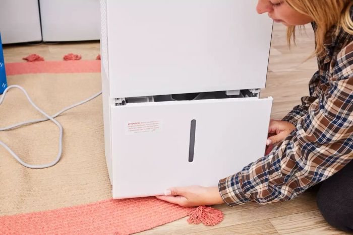 An individual removing a compartment from the Homelabs 50-Pint Wi-Fi Dehumidifier HME031003N