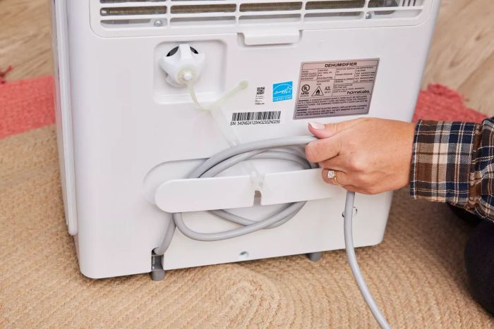 A hand adjusting the cord at the rear of the Homelabs 50-Pint Wi-Fi Dehumidifier HME031003N