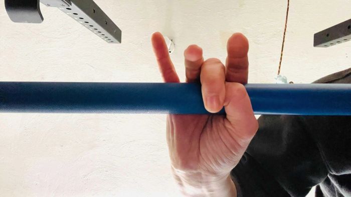 A hand gripping a barbell, demonstrating the correct thumb positioning.