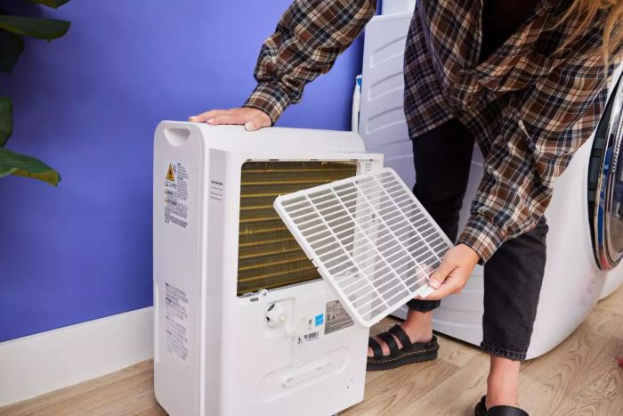 A person removing a grate from the Homelabs 50-Pint Wi-Fi Dehumidifier HME031003N