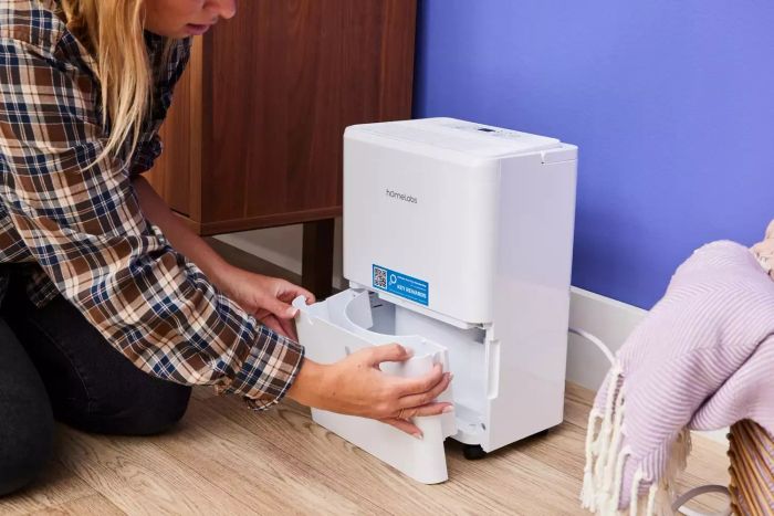 An individual removing the water tank from the Homelabs 8-Pint Dehumidifier