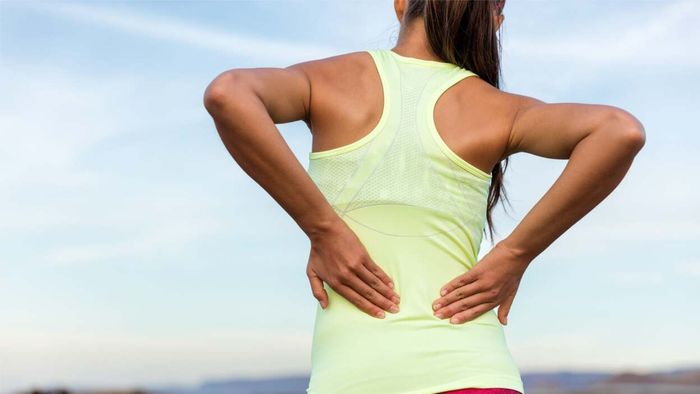 individual in exercise attire rubbing her back