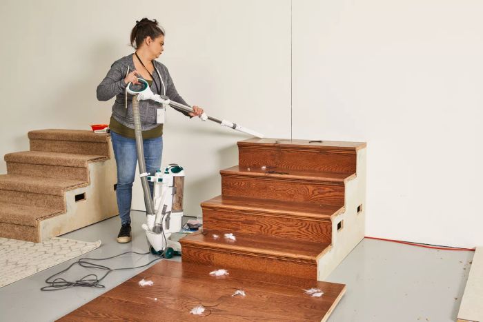 A person is cleaning wooden stairs using the hose attachment from the Shark NV501 Rotator Professional Lift-Away Upright Vacuum.