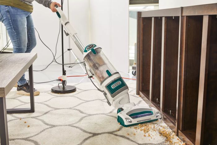 A person is vacuuming food debris off the carpet using the Shark NV501 Rotator Professional Lift-Away Upright Vacuum.