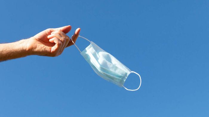 A mask resting on a person's finger while outside