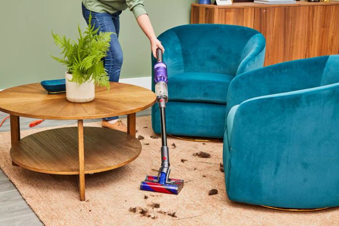 A person vacuuming around furniture with the Dyson Omni-Glide Cordless Vacuum