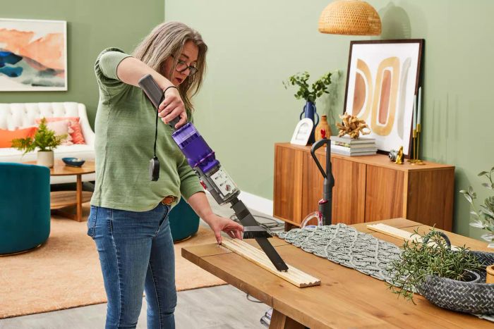 A person using the Dyson Omni-Glide Cordless Vacuum on hardwood flooring