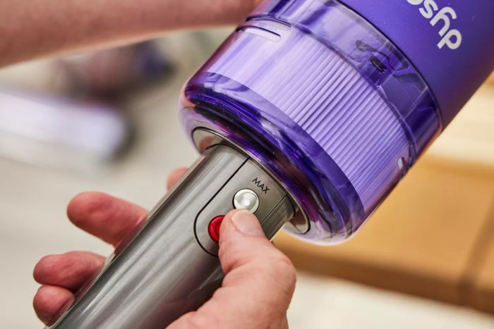 A hand pressing the power button on the Dyson Omni-Glide Cordless Vacuum