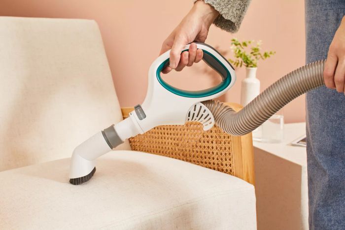 A person is cleaning a chair using the Shark NV501 Rotator Professional Lift-Away Upright Vacuum.