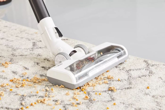 A close-up shot of a vacuum cleaner picking up food from a rug.