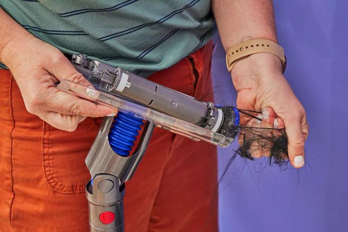 A person cleaning off the bottom of the Dyson Omni-Glide Cordless Vacuum
