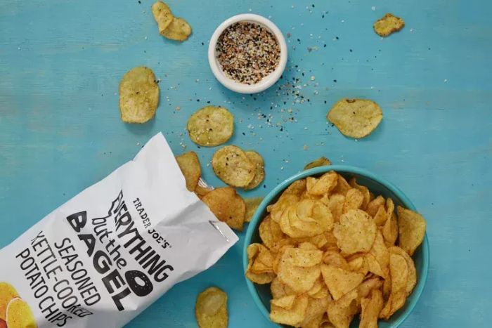 A photo of Trader Joe's Everything But The Bagel Seasoned Kettle Cooked Potato Chips showcasing the seasoning and a bowl of chips