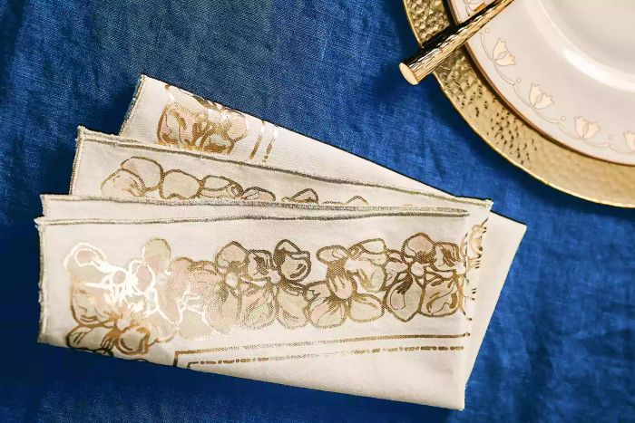 A stylish napkin and plate from the exclusive Met x Anthropologie Collection showcase a blend of elegance and artistry.