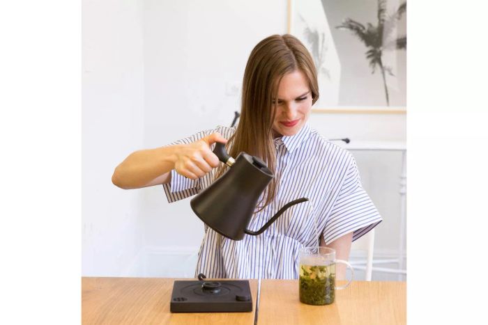 A person pouring hot water from the Fellow Stagg EKG Electric Kettle