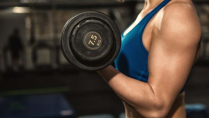 A person performing a bicep curl with a dumbbell in hand.