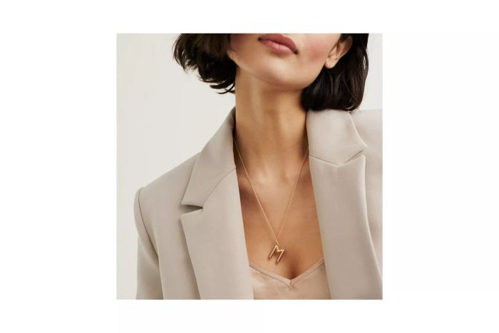 A person showcasing the Mejuri Bold Letter Pendant Necklace