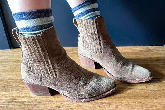 A person pairs the Tecovas The Taylor Chelsea Boots with striped socks